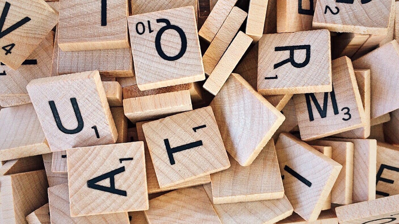 Close-up of wooden Scrabble tiles showcasing letters and numbers for word games.